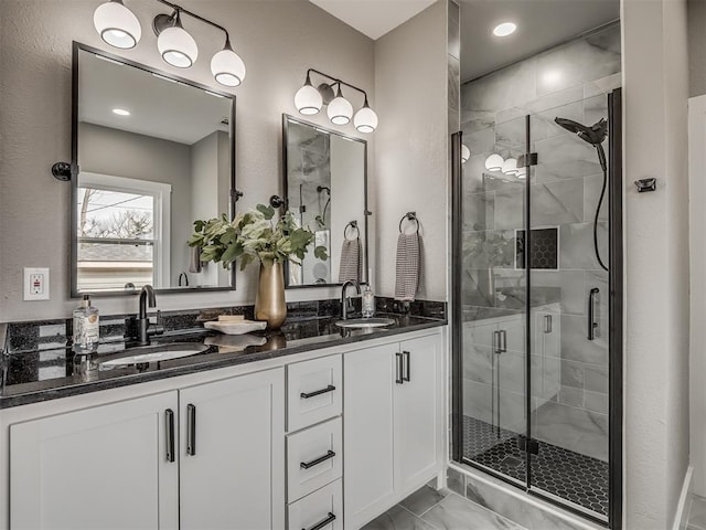 full bathroom featuring marble finish floor, double vanity, a sink, and a shower stall