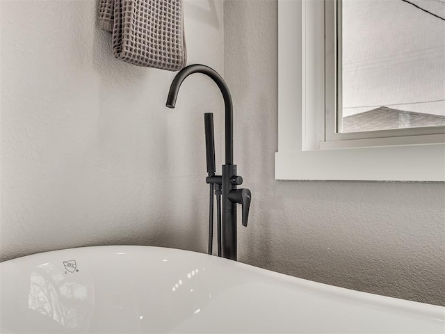 interior details with a textured wall and a freestanding bath