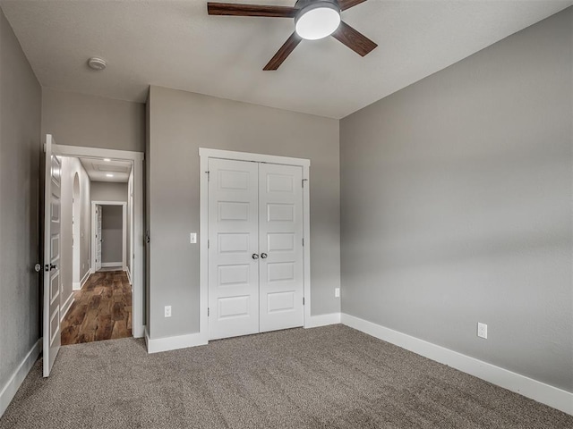 unfurnished bedroom with ceiling fan, baseboards, a closet, carpet, and attic access