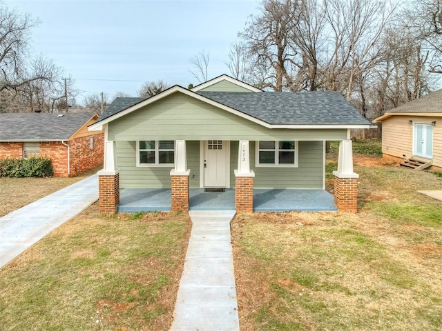 bungalow with a shingled roof, a front lawn, and a porch