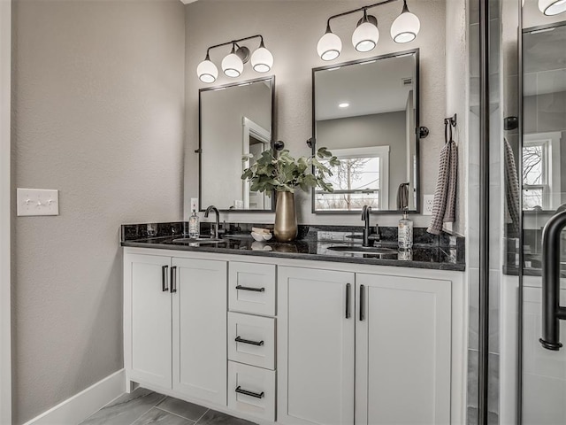 1413 NE 14th St, Oklahoma City, OK 73117 - bathroom with double vanity, marble look tiles, baseboards, and a shower with shower door