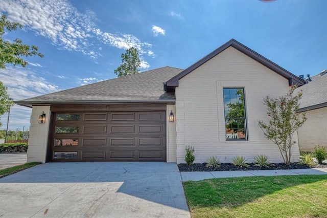 view of front facade featuring brick siding, driveway, a shingled roof, and a garage