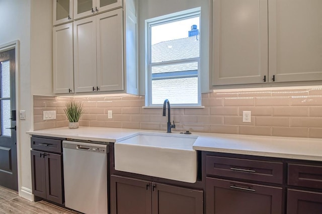 kitchen featuring a sink, light countertops, light wood-style floors, dishwasher, and backsplash