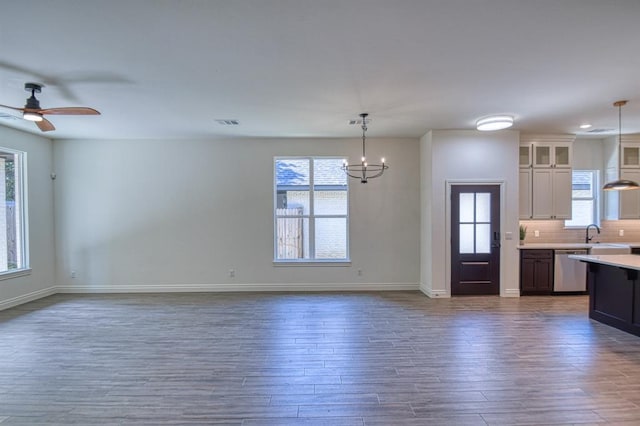 kitchen featuring tasteful backsplash, stainless steel dishwasher, dark wood finished floors, light countertops, and glass insert cabinets