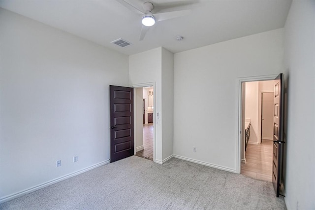 unfurnished bedroom with a ceiling fan, light colored carpet, visible vents, and baseboards