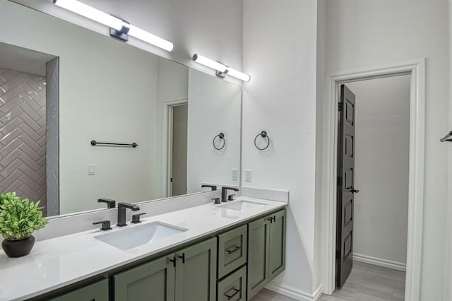 full bathroom with double vanity, baseboards, and a sink