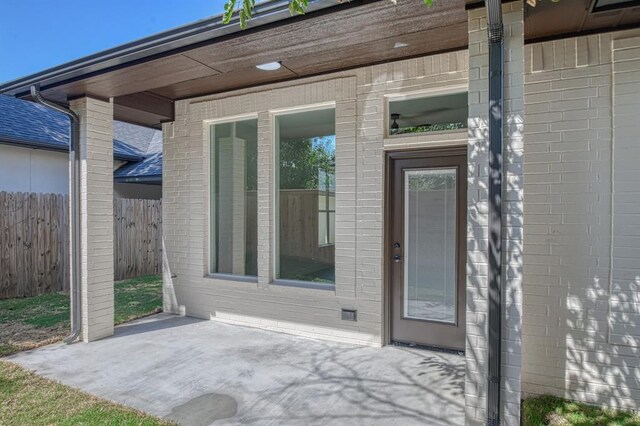 doorway to property with a patio, fence, and brick siding