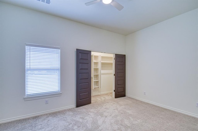 unfurnished bedroom featuring carpet, baseboards, ceiling fan, a closet, and a walk in closet