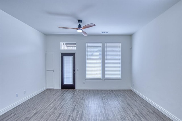 unfurnished room featuring plenty of natural light, wood finished floors, and baseboards