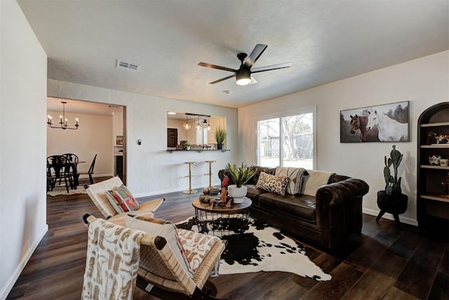 living area featuring ceiling fan with notable chandelier, dark wood finished floors, visible vents, and baseboards