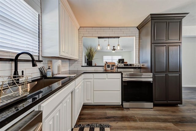 kitchen with tasteful backsplash, dark countertops, dark wood-type flooring, white cabinets, and stainless steel range with electric cooktop