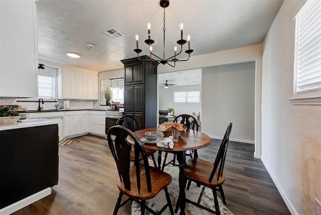 dining space with dark wood-style floors, visible vents, and baseboards