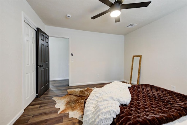 bedroom with a ceiling fan, visible vents, baseboards, and wood finished floors