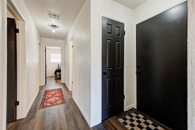 interior space featuring baseboards, visible vents, and dark wood-type flooring