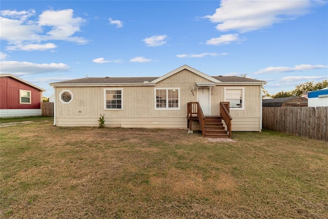 rear view of property featuring fence and a yard