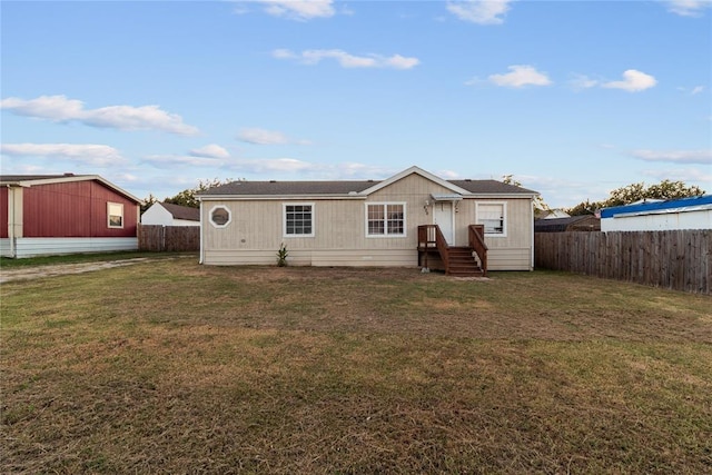 back of house featuring entry steps, a lawn, and a fenced backyard