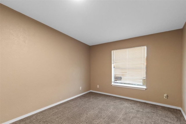 carpeted spare room featuring baseboards