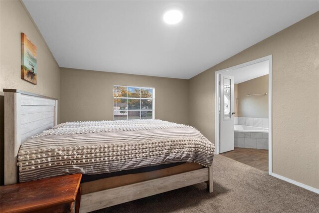 bedroom with a textured wall, vaulted ceiling, connected bathroom, and carpet flooring