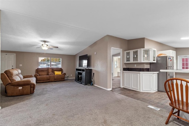 living area featuring baseboards, vaulted ceiling, visible vents, and dark colored carpet