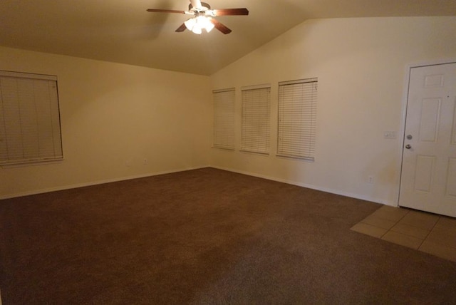 spare room featuring ceiling fan, dark carpet, and vaulted ceiling