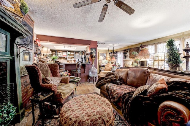 living area with a textured ceiling, ceiling fan, and wood finished floors