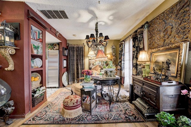 dining space featuring a chandelier, visible vents, light wood-style floors, and a textured ceiling