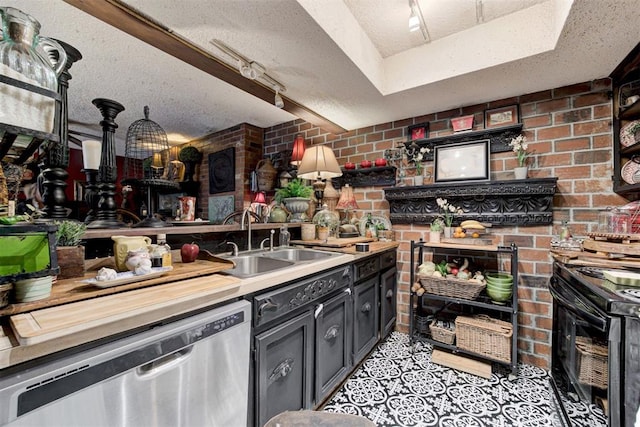 kitchen featuring brick wall, a sink, a textured ceiling, and stainless steel dishwasher