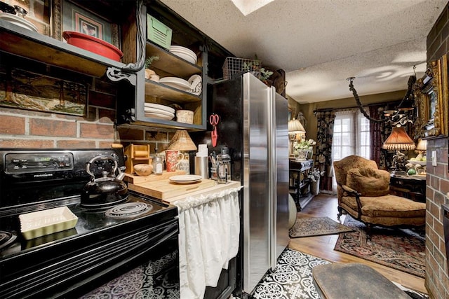 kitchen featuring black electric range, wood finished floors, a textured ceiling, and freestanding refrigerator