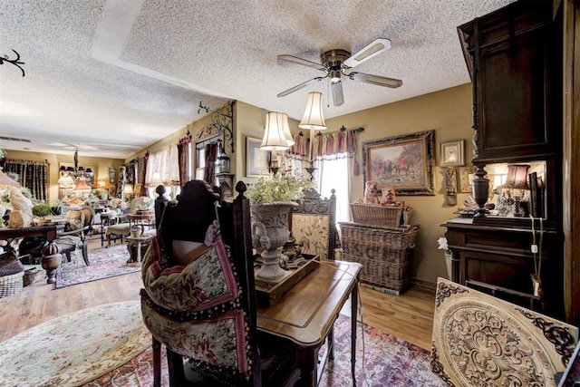 dining area with light wood-style floors, a textured ceiling, and ceiling fan with notable chandelier