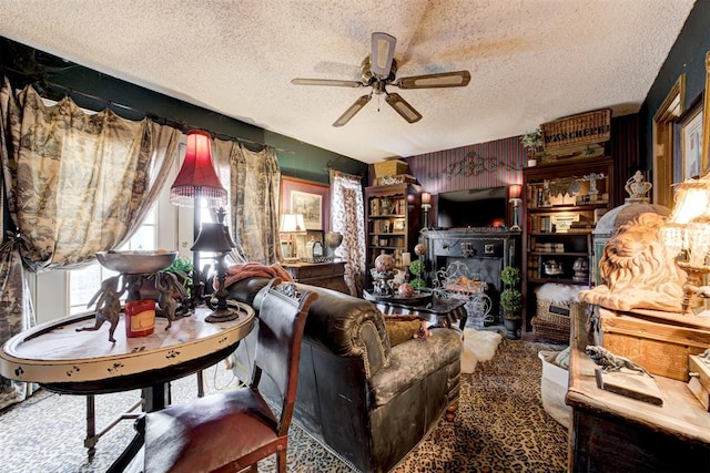 living area with a warm lit fireplace, ceiling fan, and a textured ceiling