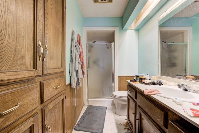 bathroom with a wainscoted wall, a shower stall, vanity, and tile patterned floors