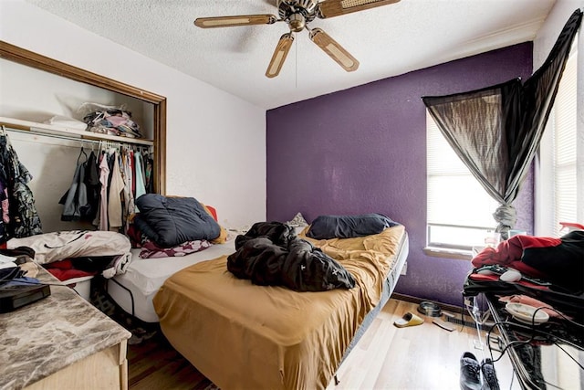 bedroom featuring a ceiling fan, a closet, a textured ceiling, and wood finished floors