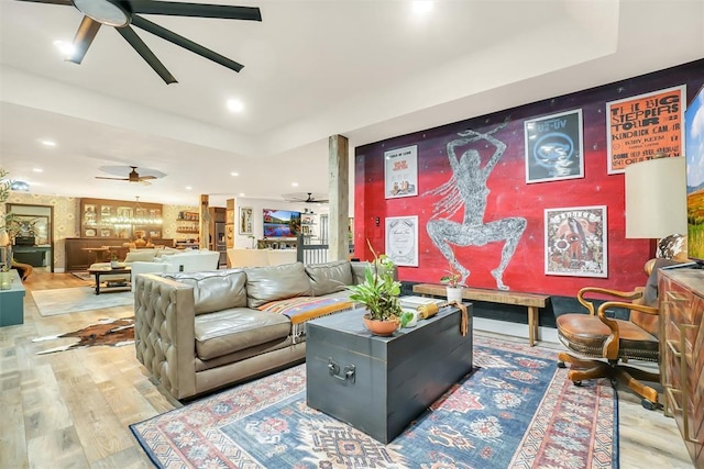 living room with a raised ceiling, light hardwood / wood-style flooring, and ceiling fan