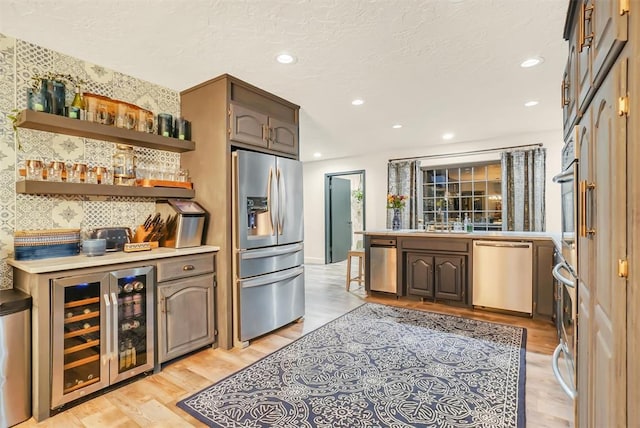 kitchen with light wood-type flooring, dark brown cabinets, beverage cooler, and stainless steel appliances