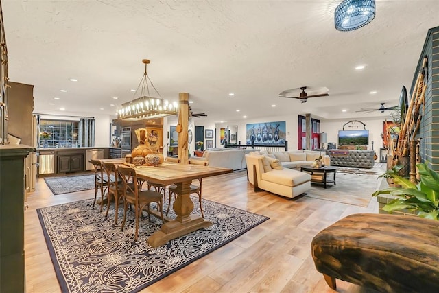 dining room with ceiling fan, light wood-type flooring, and a textured ceiling