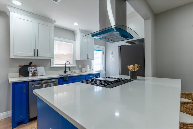 kitchen with stainless steel dishwasher, a sink, blue cabinetry, and island range hood