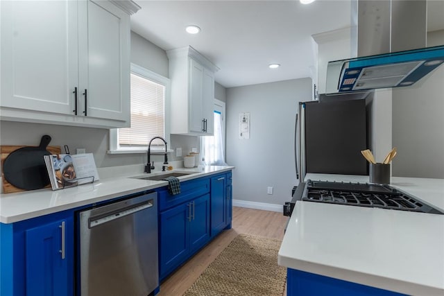 kitchen with a sink, appliances with stainless steel finishes, blue cabinetry, and island range hood