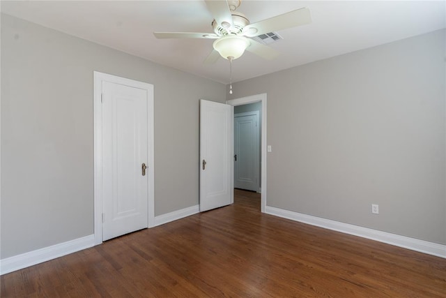 unfurnished bedroom with a closet, visible vents, a ceiling fan, wood finished floors, and baseboards