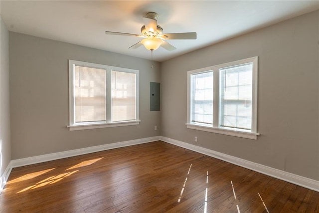 empty room featuring ceiling fan, electric panel, baseboards, and wood finished floors