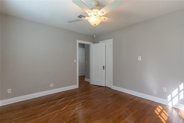 spare room with ceiling fan, wood finished floors, visible vents, and baseboards