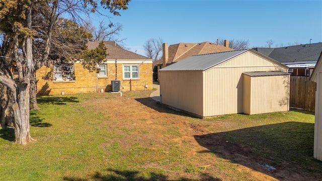 view of yard featuring central AC unit, a storage unit, an outdoor structure, and fence