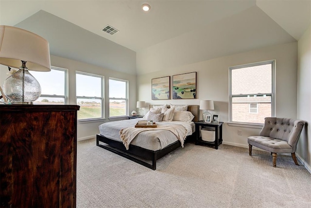 bedroom featuring multiple windows, lofted ceiling, and light colored carpet