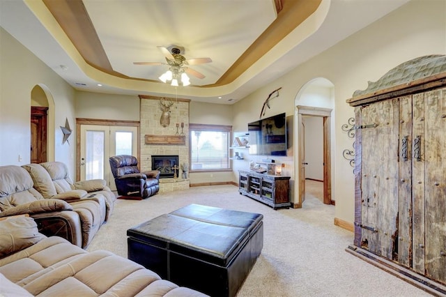 4220 Caribou St, Tuttle, OK 73089 - living room with light carpet, a tray ceiling, arched walkways, ceiling fan, and a fireplace