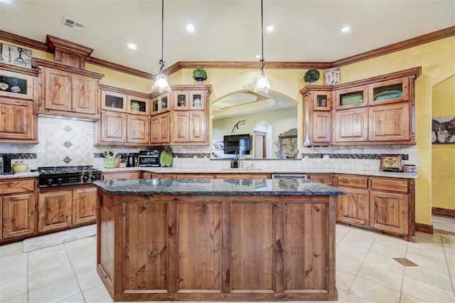 4220 Caribou St, Tuttle, OK 73089 - kitchen featuring decorative backsplash, gas stovetop, light tile patterned floors, ornamental molding, and a kitchen island