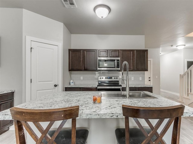 kitchen featuring backsplash, dark brown cabinets, and stainless steel appliances