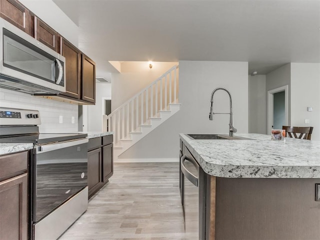 kitchen featuring a center island with sink, stainless steel appliances, light hardwood / wood-style flooring, sink, and a kitchen breakfast bar