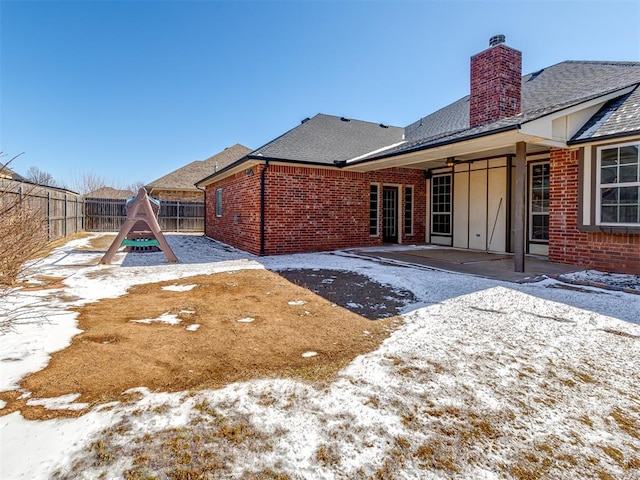 yard covered in snow with a patio area, a playground, and a fenced backyard