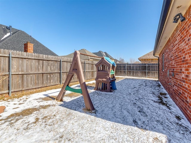 snow covered playground with a fenced backyard and a playground