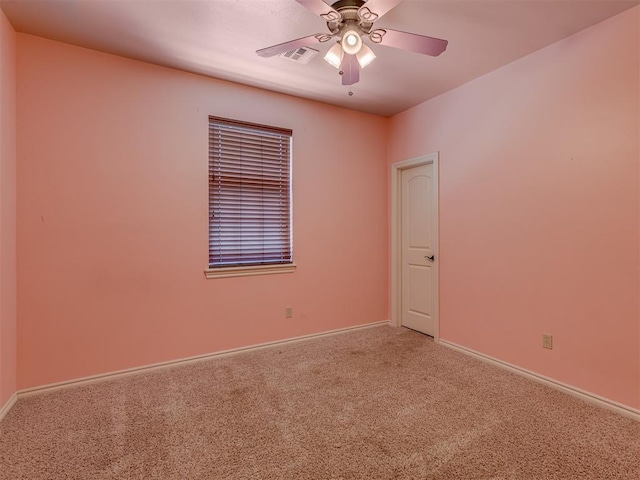 carpeted spare room featuring baseboards, visible vents, and a ceiling fan