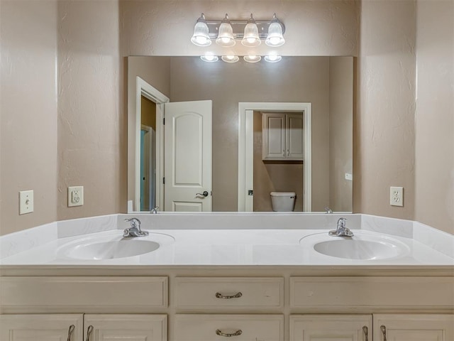 full bathroom with toilet, double vanity, and a sink